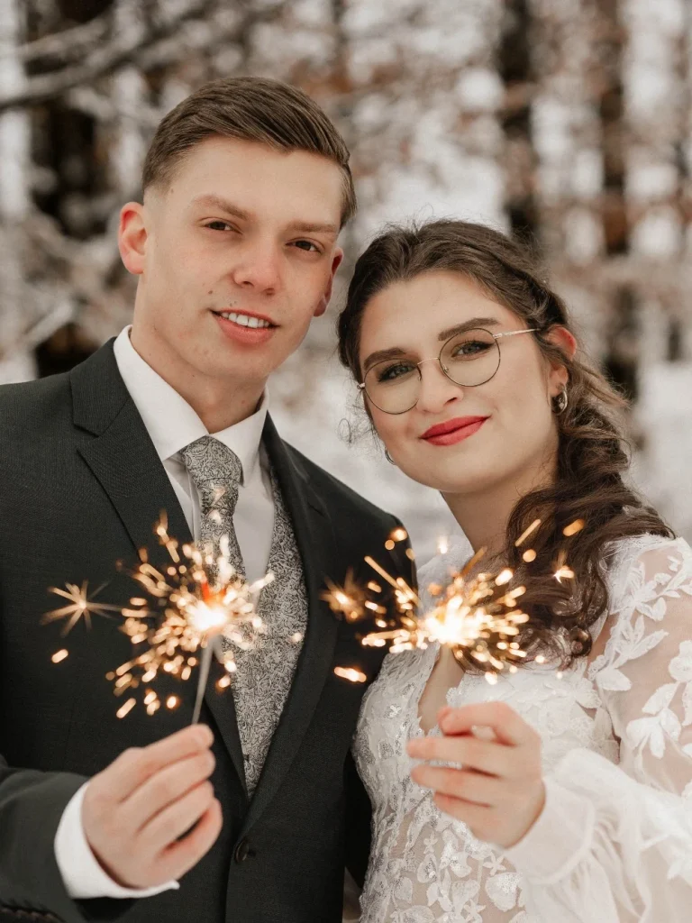 Winter Wedding im Schnee, Brautpaar hält Wunderkerzen in der Hand und ist vom Schnee umgeben